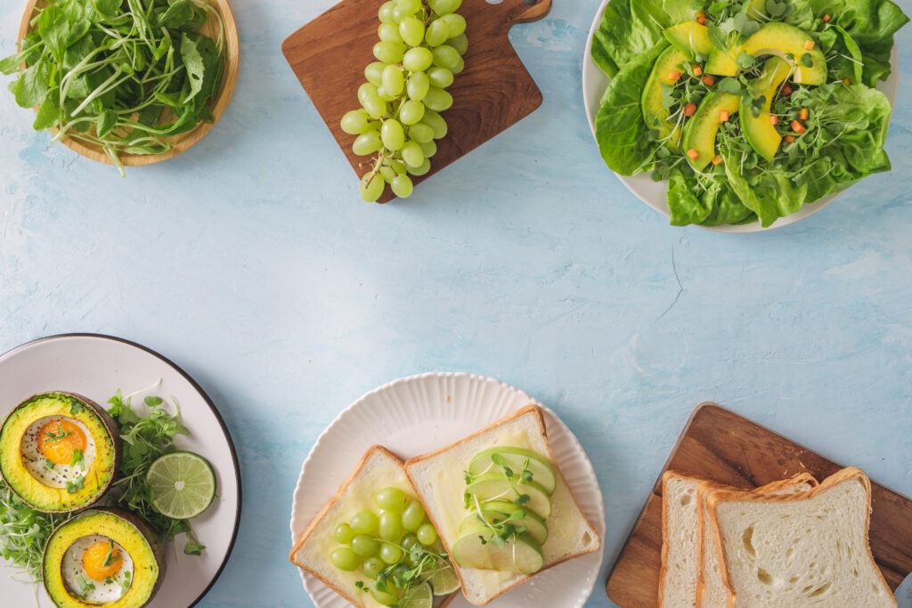 Healthy vegan breakfast. diet. baked avocado with egg and fresh salad from arugula, toast and butter. on a white marble plate, a light concrete table. a cup of coffee. copy space