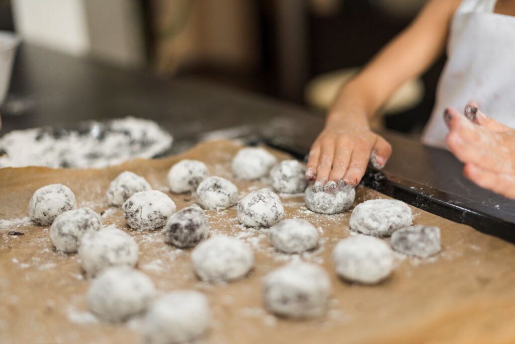Girl s hand applying flour raw cookies